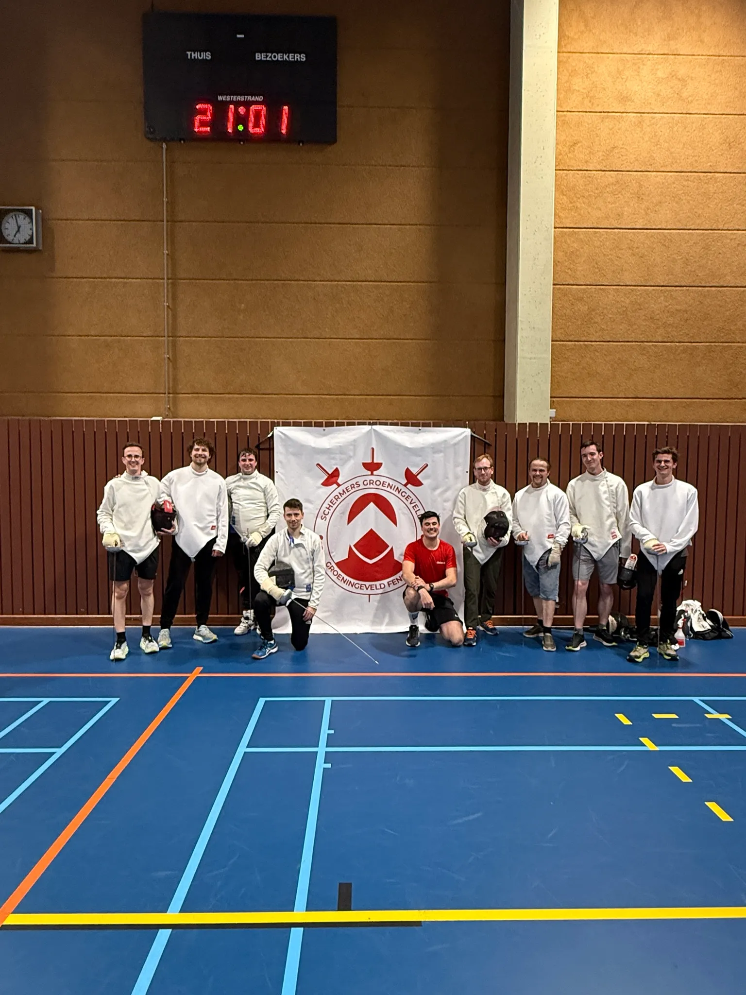 Groepsfoto van de deelnemers in schermvest voor de clubvlag van Schermers Groeningeveld